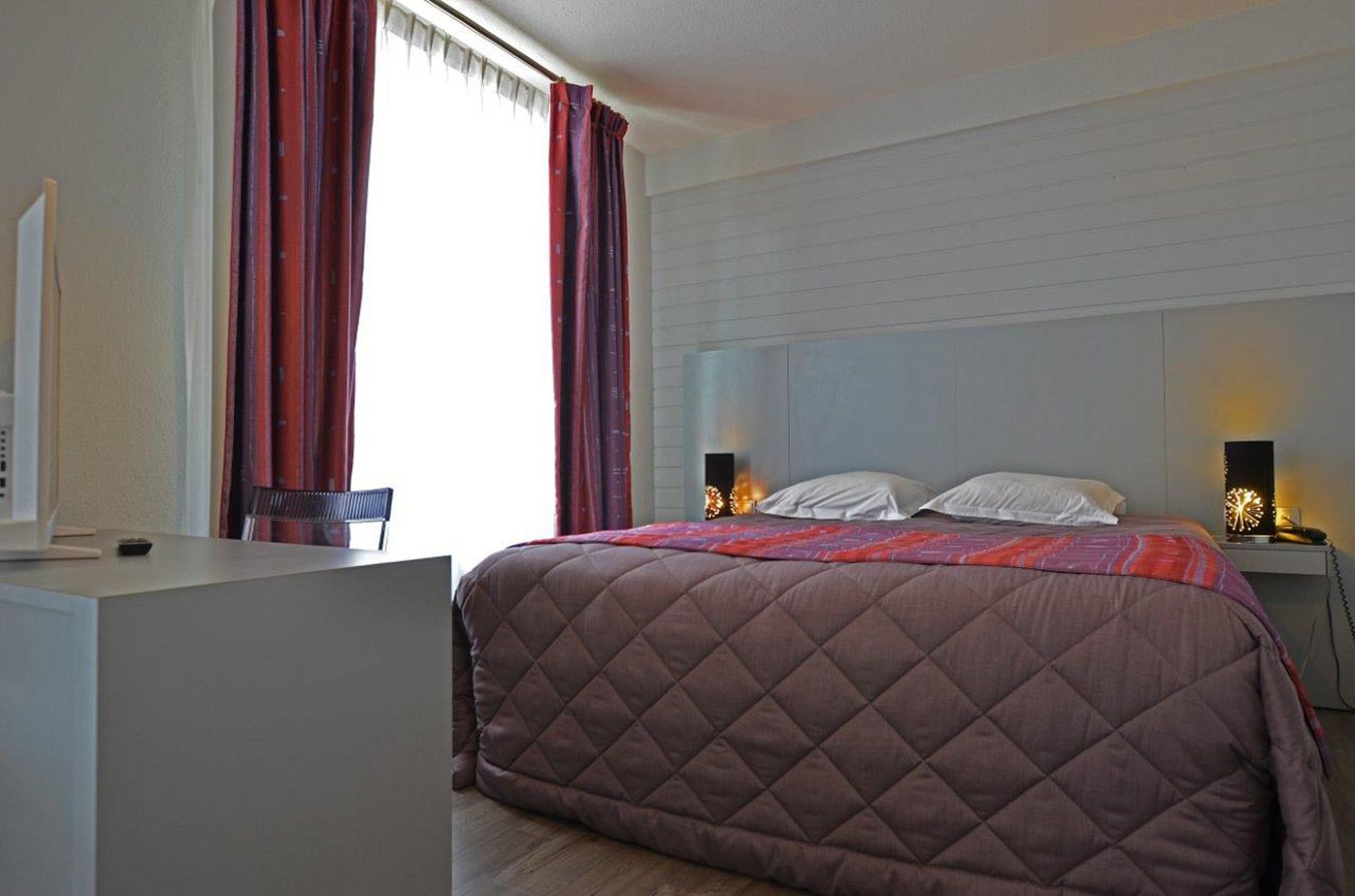 Un dormitorio con una cama grande, una mesita de noche y un escritorio.