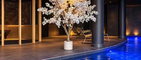 A pool area with a white flower arrangement, lounge chairs, and a modern architectural design.