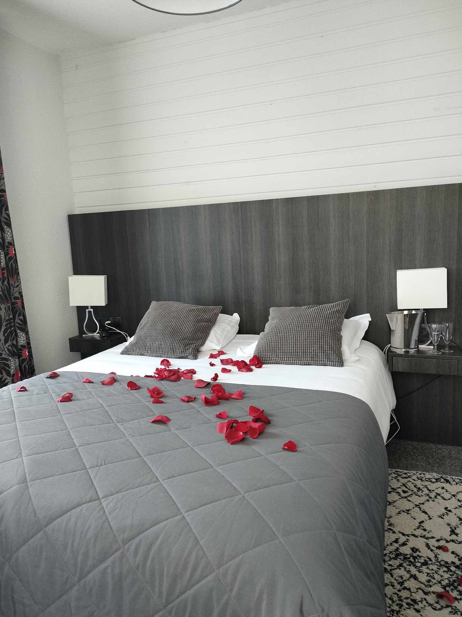 A hotel room with a large bed, two bedside tables, and a headboard.