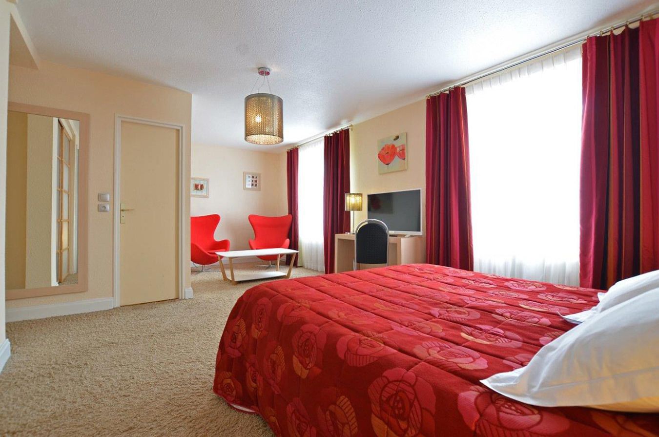A hotel room with a large bed, a desk, a chair, and a television.