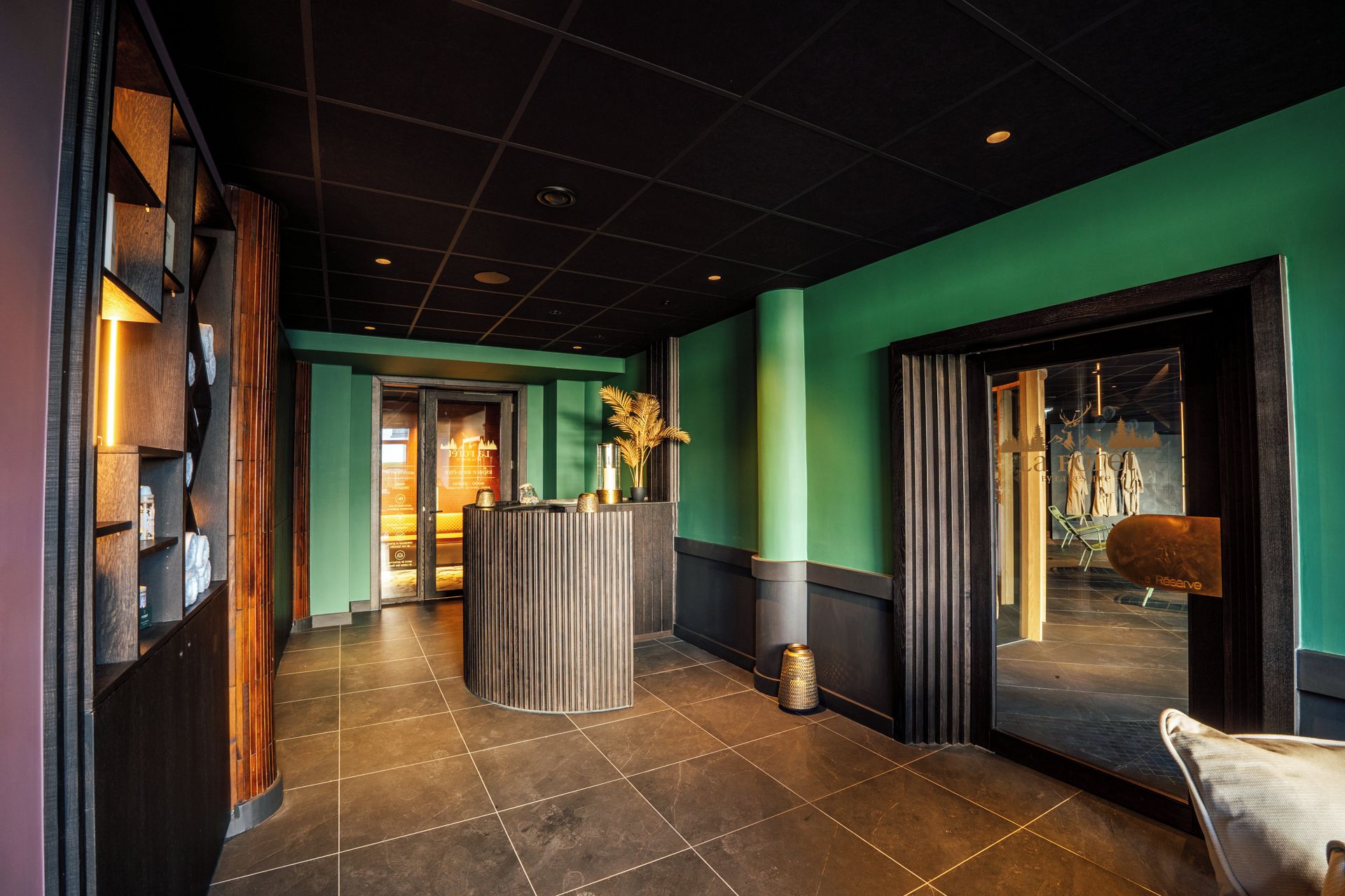 Eine moderne Hotellobby mit einer Rezeption, einer Sitzecke und Blick ins Freie.
