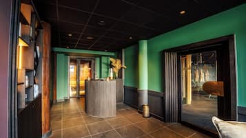 Eine moderne Hotellobby mit einer Rezeption, einer Sitzecke und Blick ins Freie.