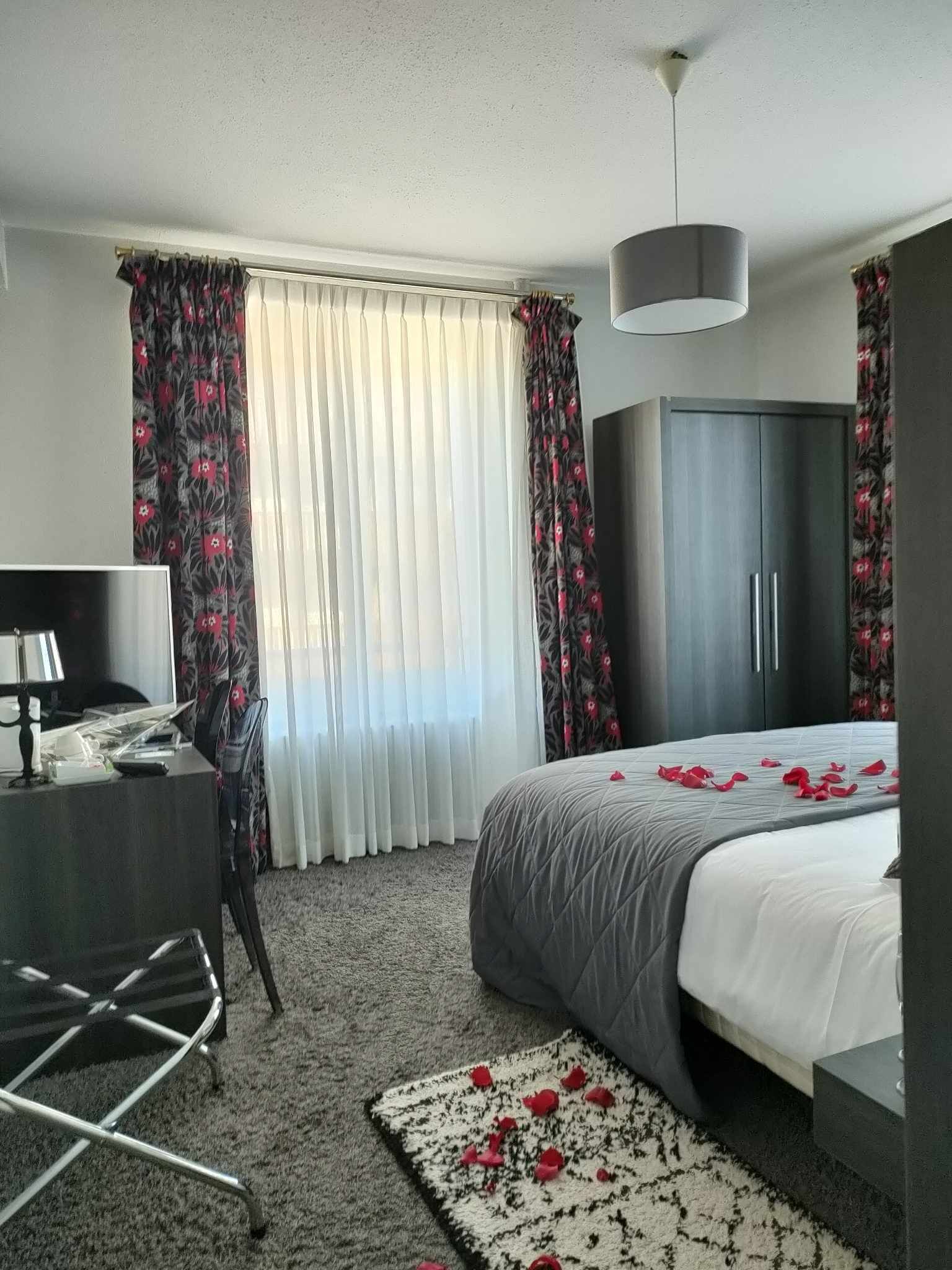 A hotel room with a bed, a desk, a TV, and a wardrobe.