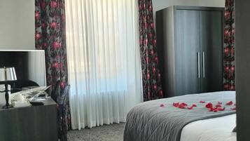 A hotel room with a bed, a desk, a TV, and a wardrobe.