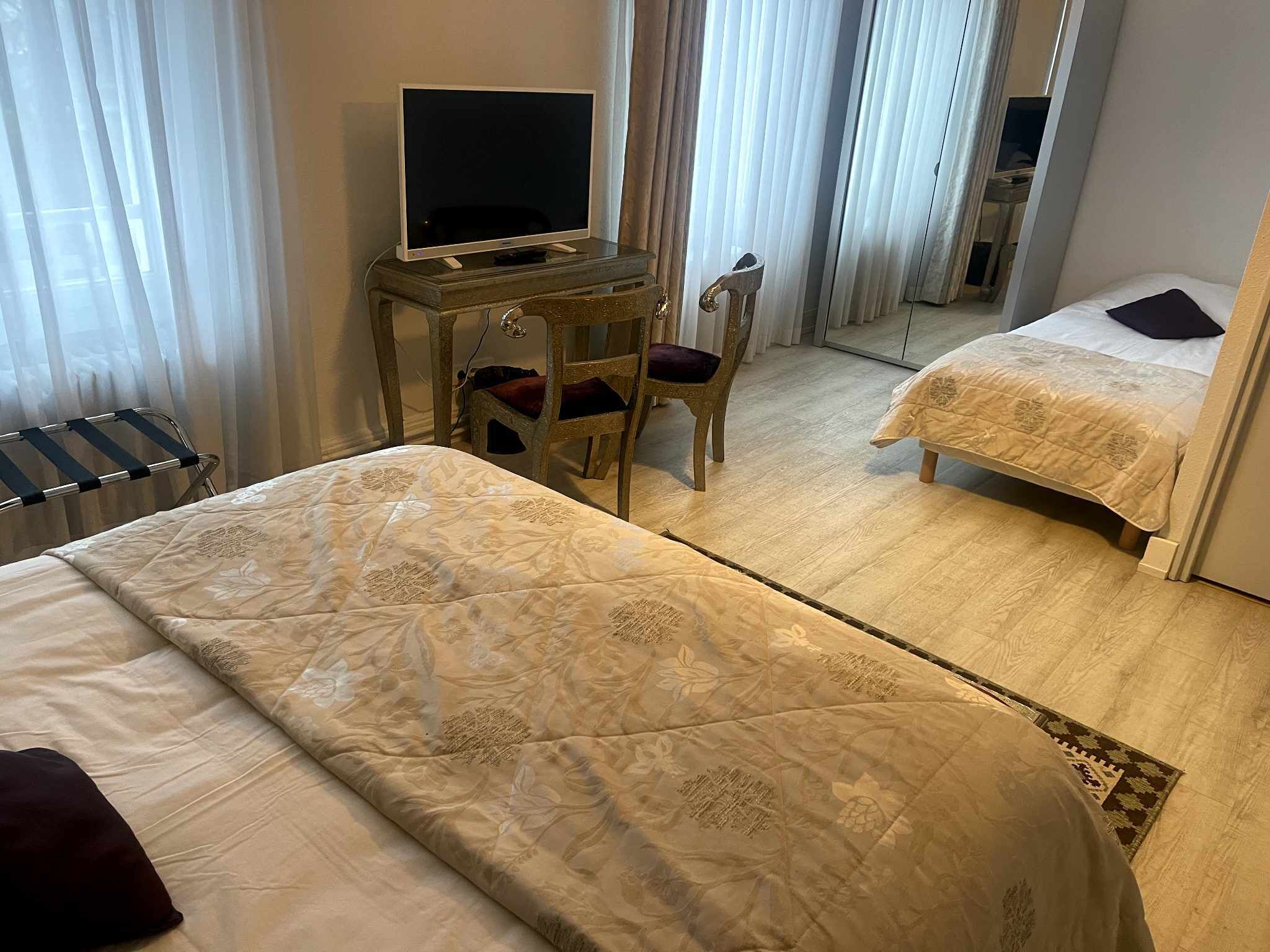 Habitación de hotel con dos camas, un escritorio con televisor y una silla.