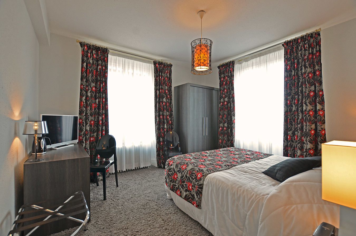 Ein Hotelzimmer mit einem Bett, einem Schreibtisch, einem Sessel und einem Fernseher.