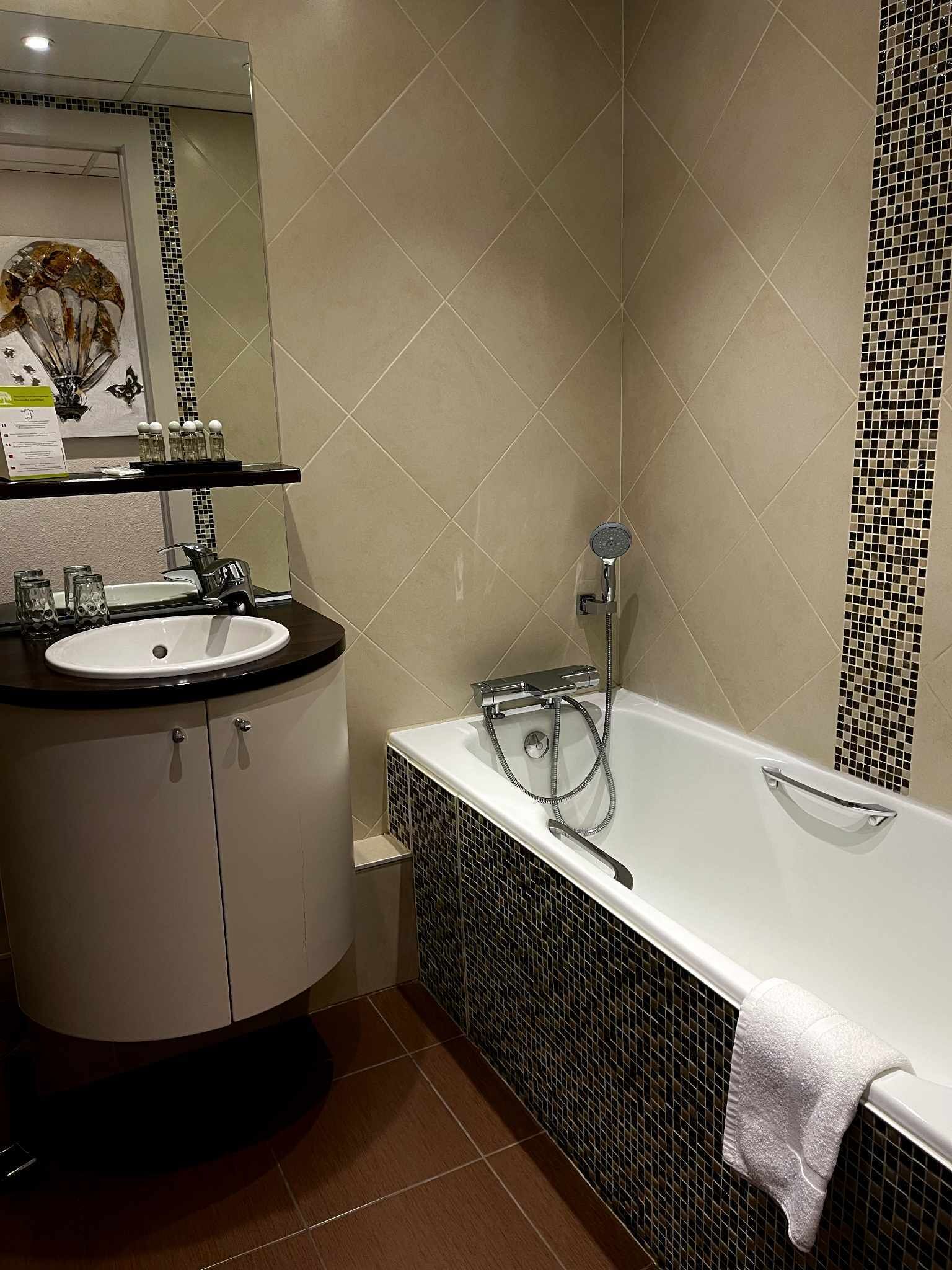 A modern bathroom with a white sink, a glass shower enclosure, and a tiled floor.