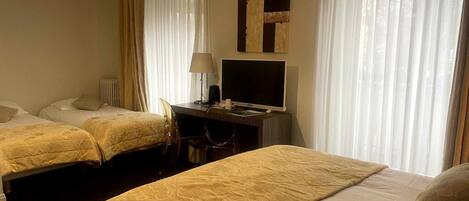 Habitación de hotel con dos camas, un escritorio con televisor y una lámpara.