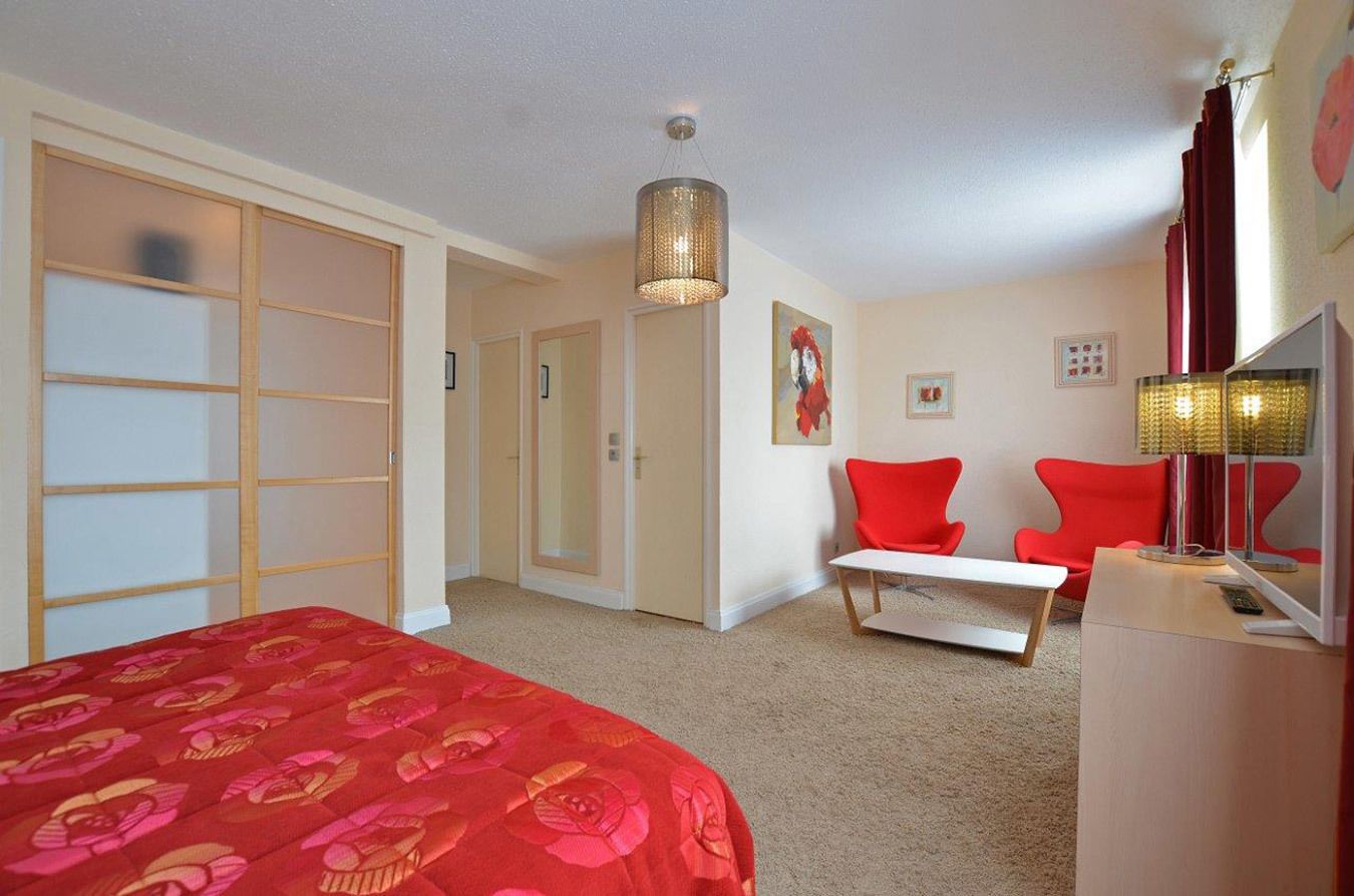 A hotel room with a bed, a desk, a chair, and a wardrobe.