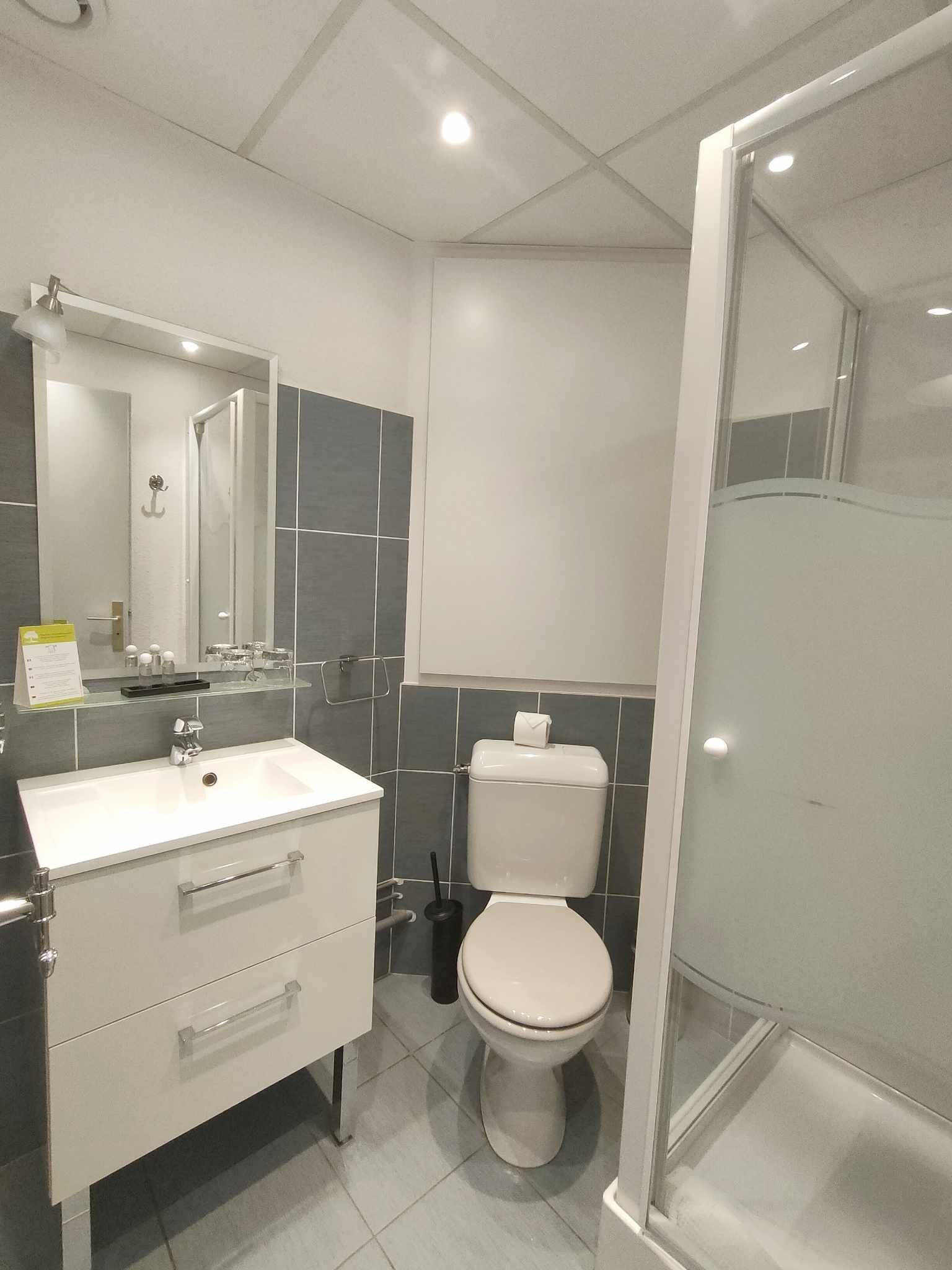 Une salle de bain moderne avec un lavabo blanc, un miroir et des toilettes.