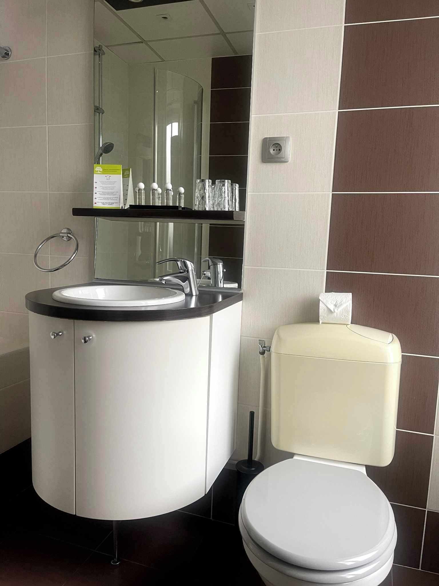 Un baño moderno con un lavabo redondo, un inodoro y una cabina de ducha de vidrio.