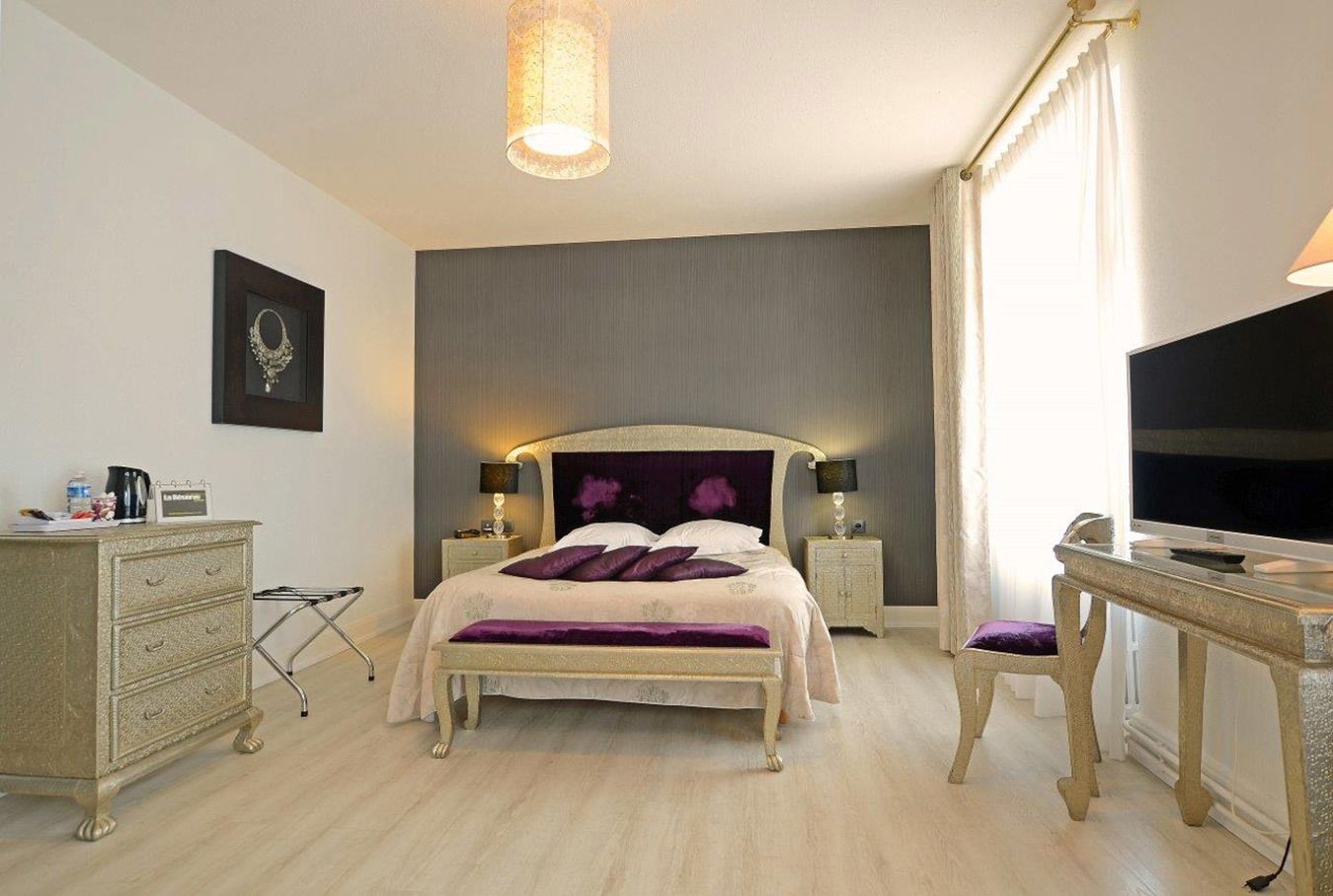 Une chambre d’hôtel comprenant un lit, des tables de chevet, un bureau, une télévision et une armoire.