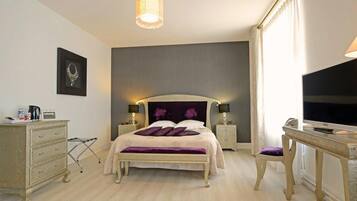Une chambre d’hôtel comprenant un lit, des tables de chevet, un bureau, une télévision et une armoire.