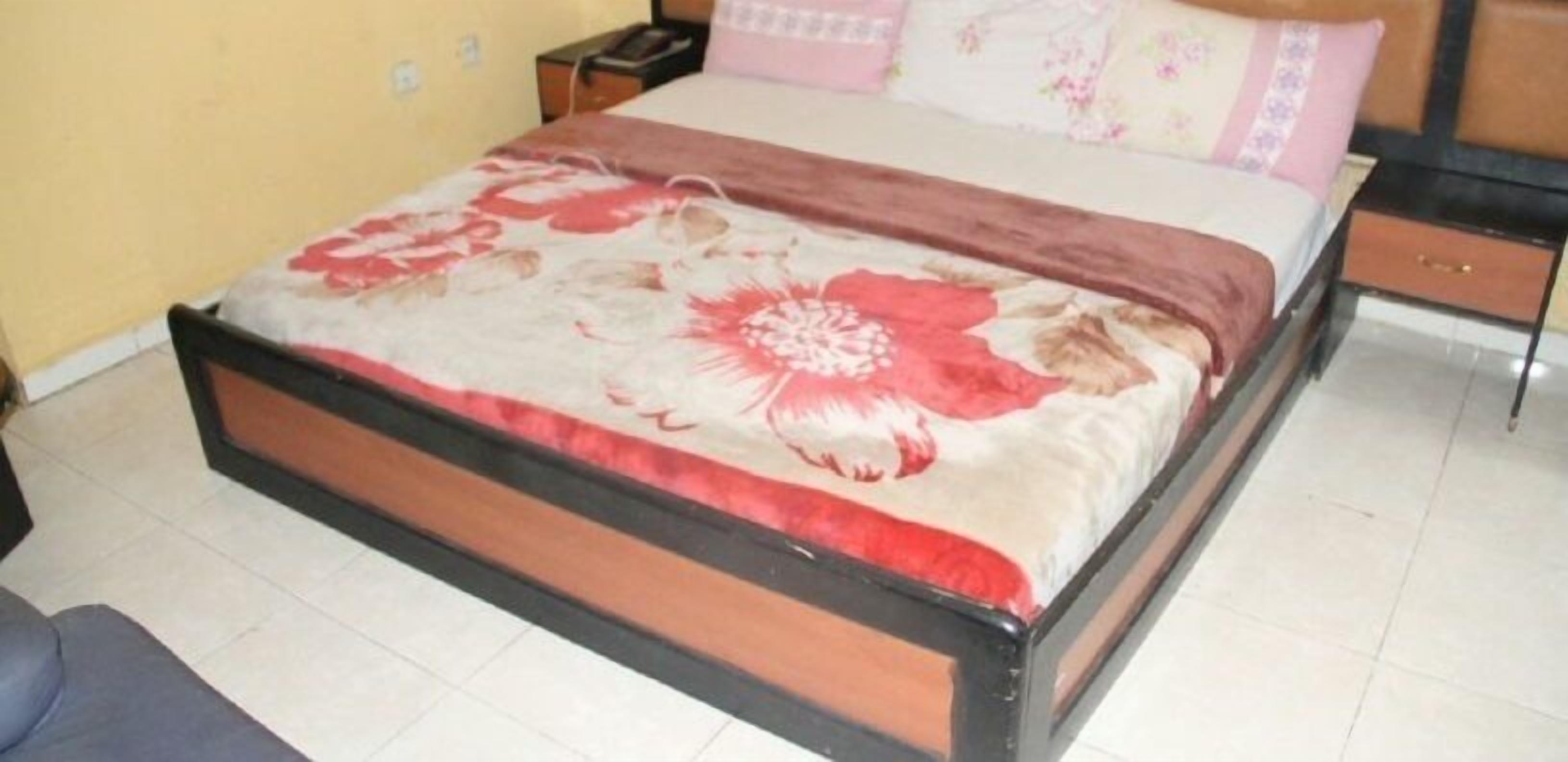A bed with a floral bedspread, a nightstand, and a bedside table with a lamp.