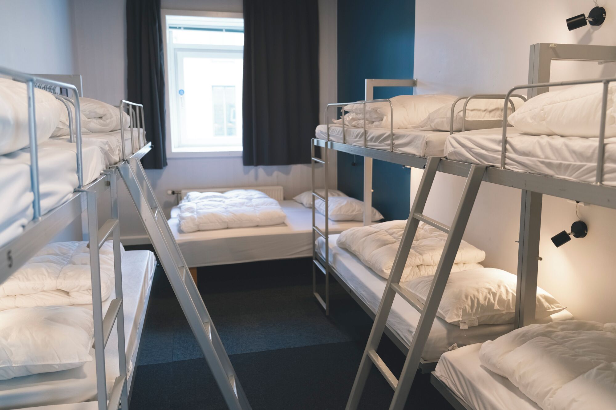 Un dormitorio con literas, una ventana con cortinas y un radiador.