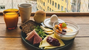 Una mesa de desayuno con diversos alimentos y bebidas en un balcón con vistas a la ciudad.
