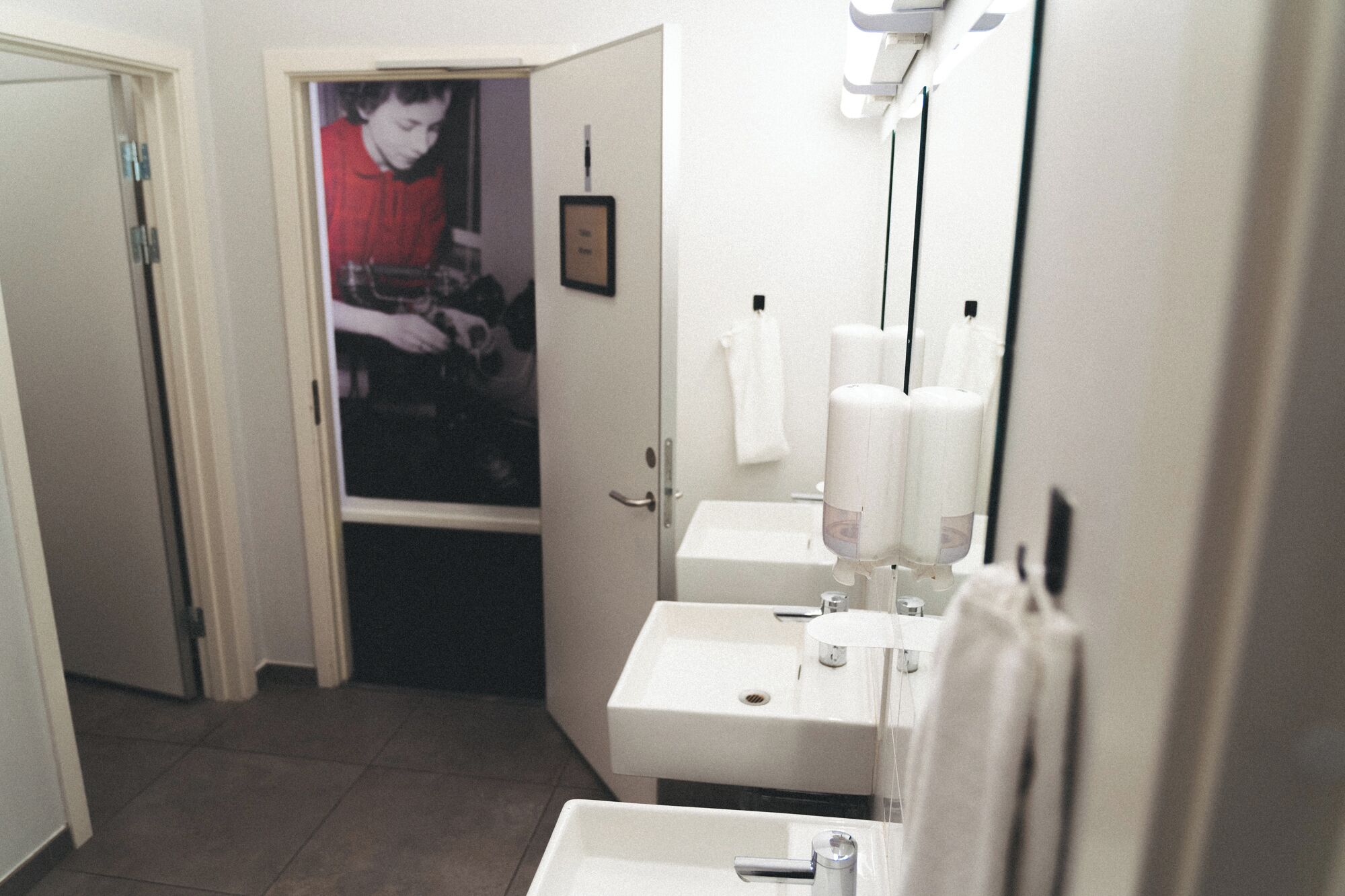 A bathroom with two sinks, a mirror, and a poster on the wall.