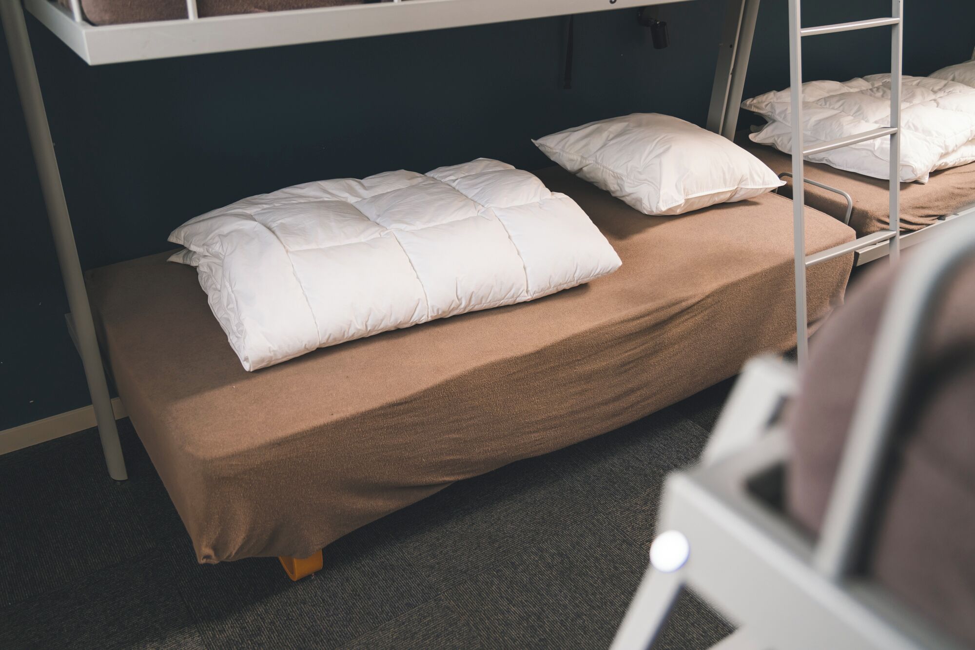 Un lit superposé avec un matelas marron et des oreillers blancs.