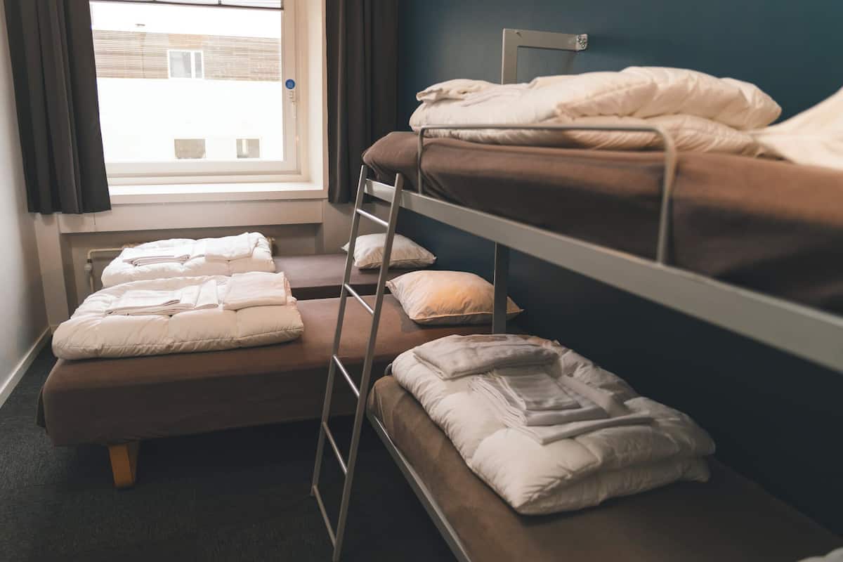 A dormitory room with bunk beds, a window, and a view of the outside.