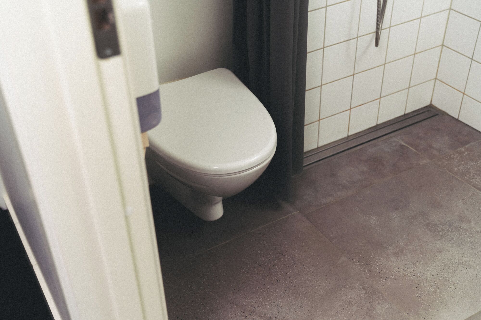 A toilet in a bathroom with a tiled floor.