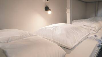 A single bed with white bedding and a wall-mounted light fixture.