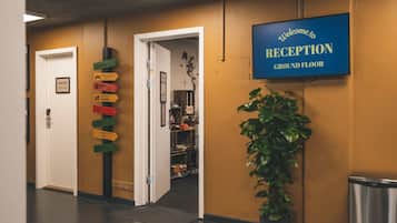 Un espace d’accueil avec une pancarte indiquant : « Bienvenue à la réception, au rez-de-chaussée ».
