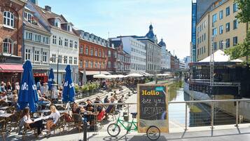 A bustling outdoor café with tables and chairs, a bicycle, and a signboard.