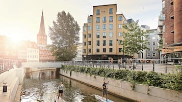 Een gracht met twee peddelplanken, een brug en gebouwen op de achtergrond.