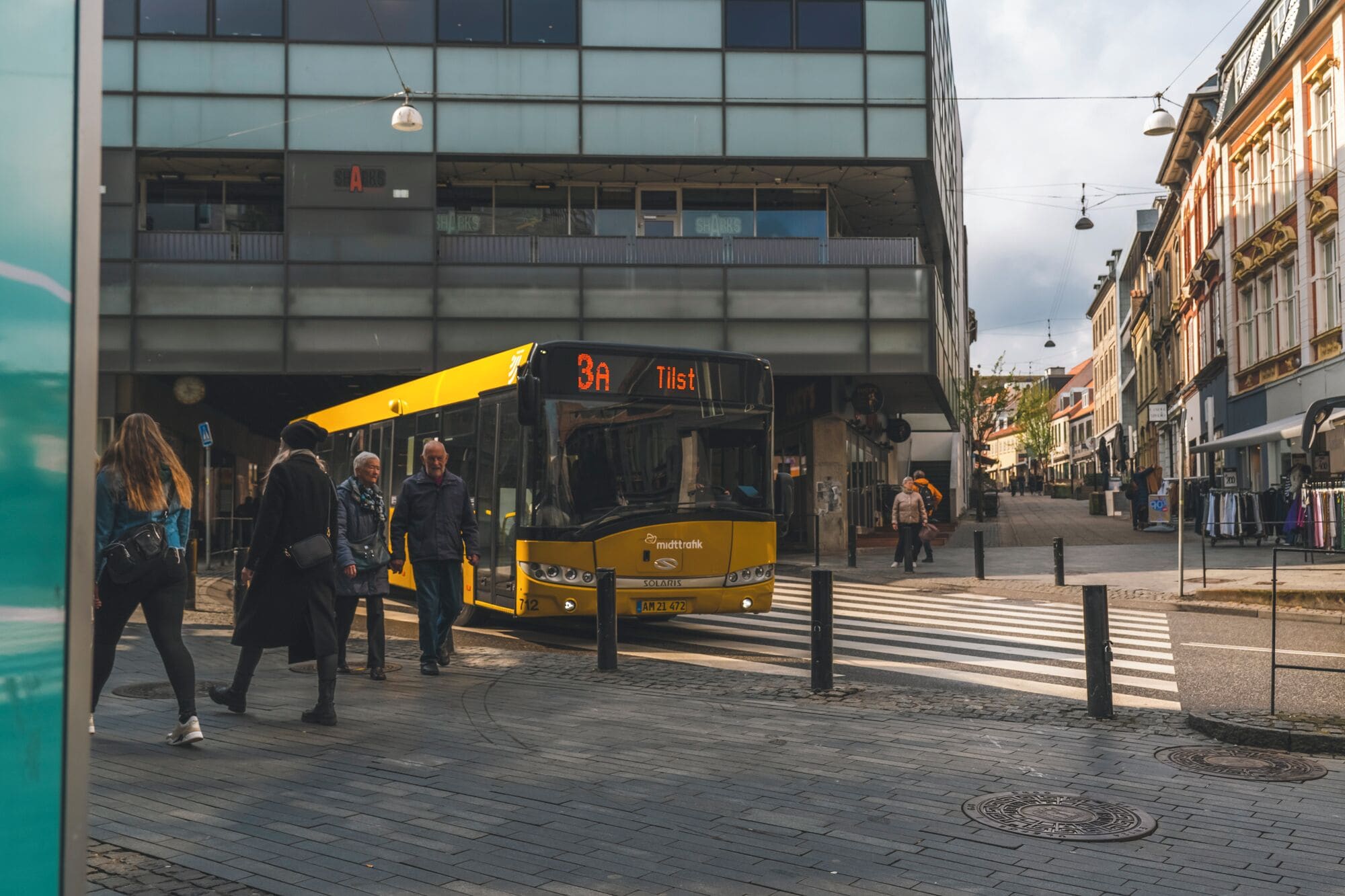 A yellow bus with the destination 'Tilst' on a city street.