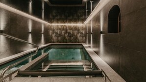 Una piscina interior moderna con diseño minimalista, rodeada de paredes con un patrón texturizado.