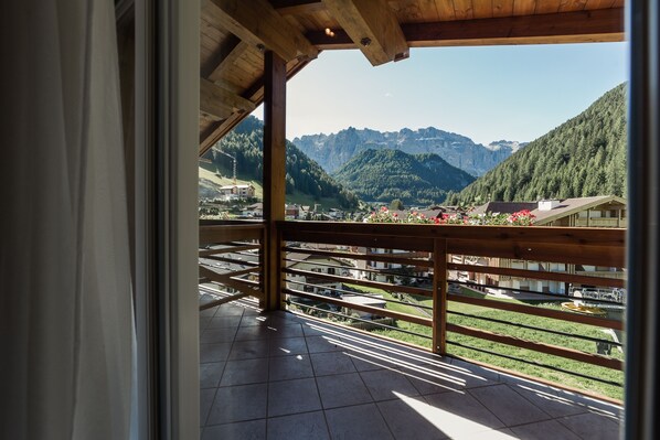 A balcony with a wooden railing overlooking a mountainous landscape. - Hotel Freina (Selva di Val Gardena)