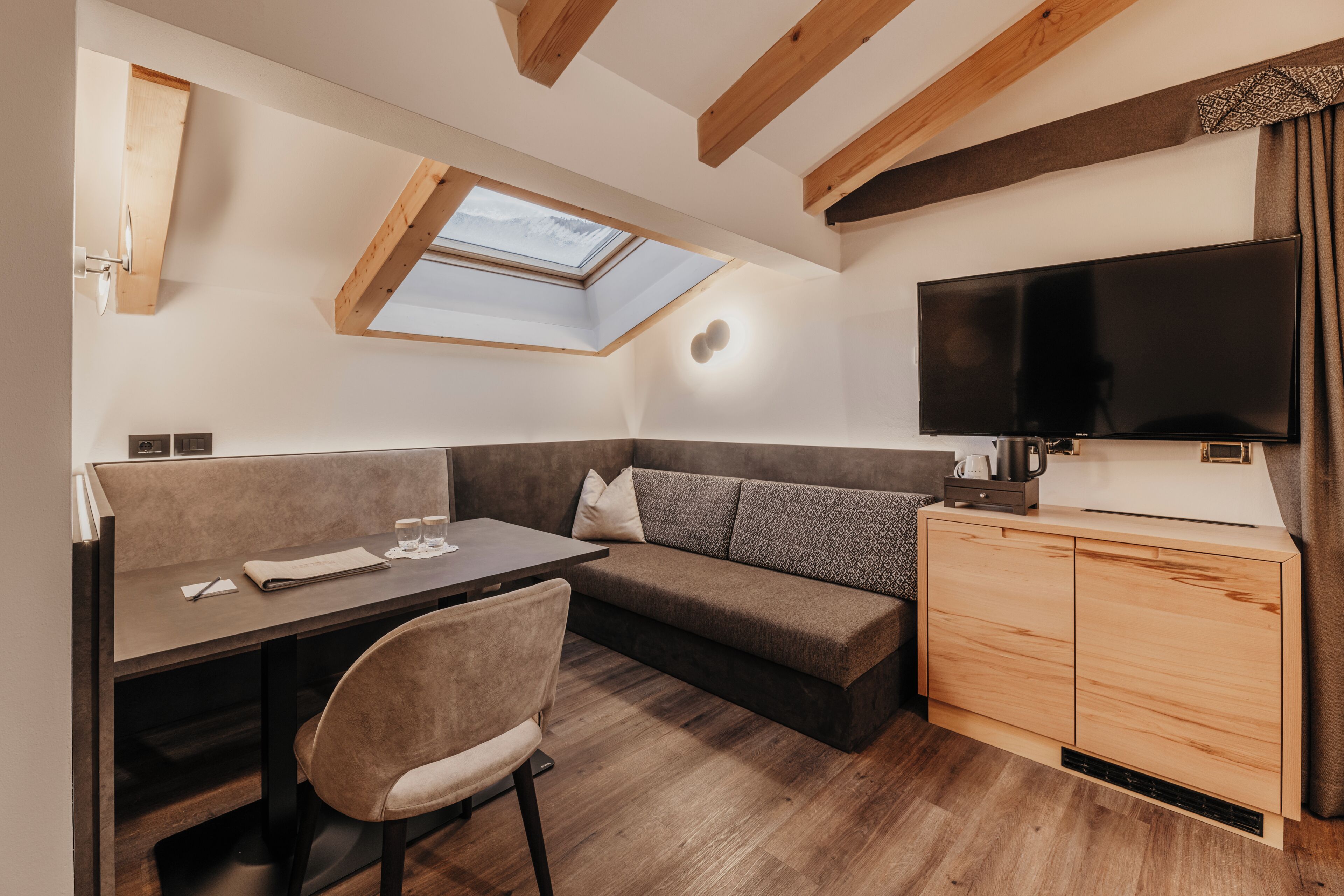 Un espacio habitable compacto con sofá, una mesita, televisor y una pequeña cocina.