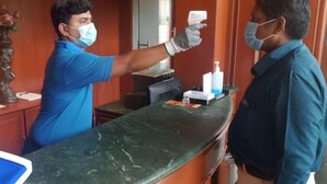 Uma receção com balcão de mármore, um certificado emoldurado e um vaso com flores.