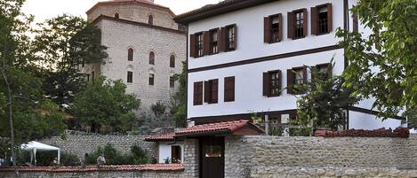 A historic building with a prominent tower and a white facade with brown shutters.
