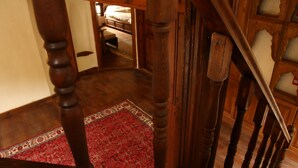 A wooden staircase with a red patterned rug at the bottom.
