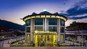 A hotel with a curved facade, balconies, and a crown symbol on the roof. - Exelans Hotel (Fethiye)