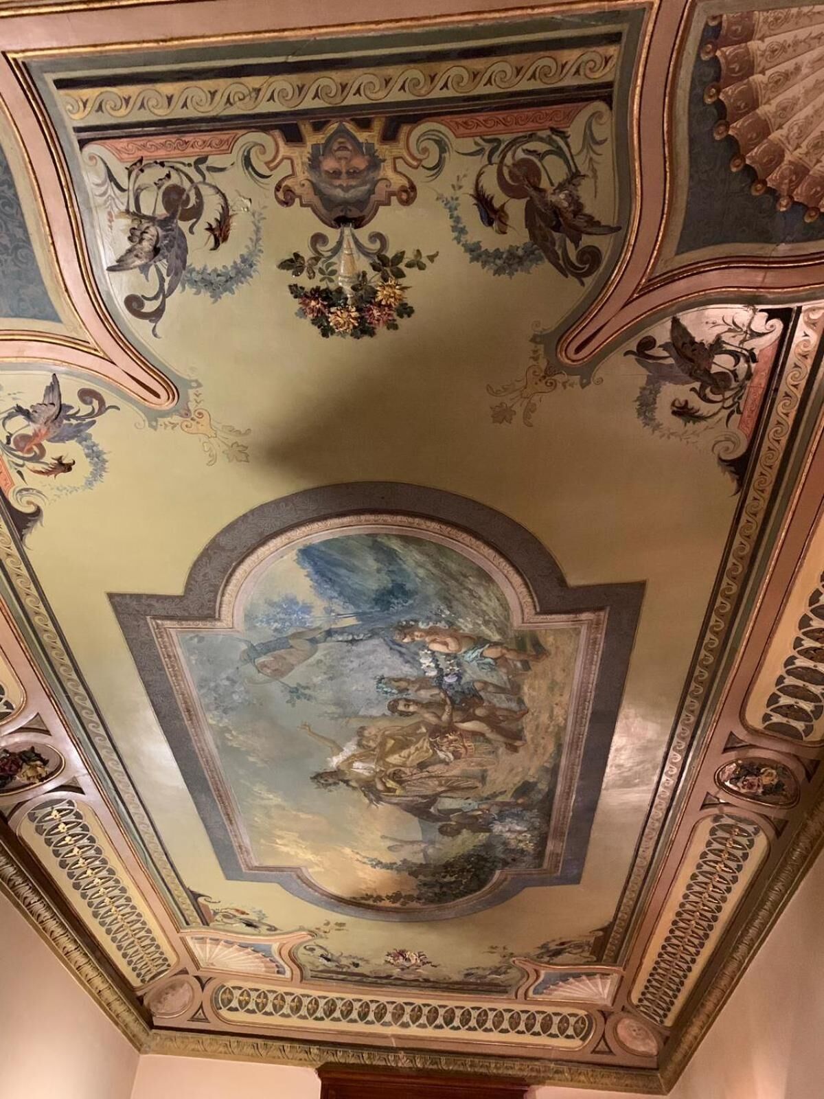 A ceiling with ornate frescoes and a central circular painting depicting a mythological scene.