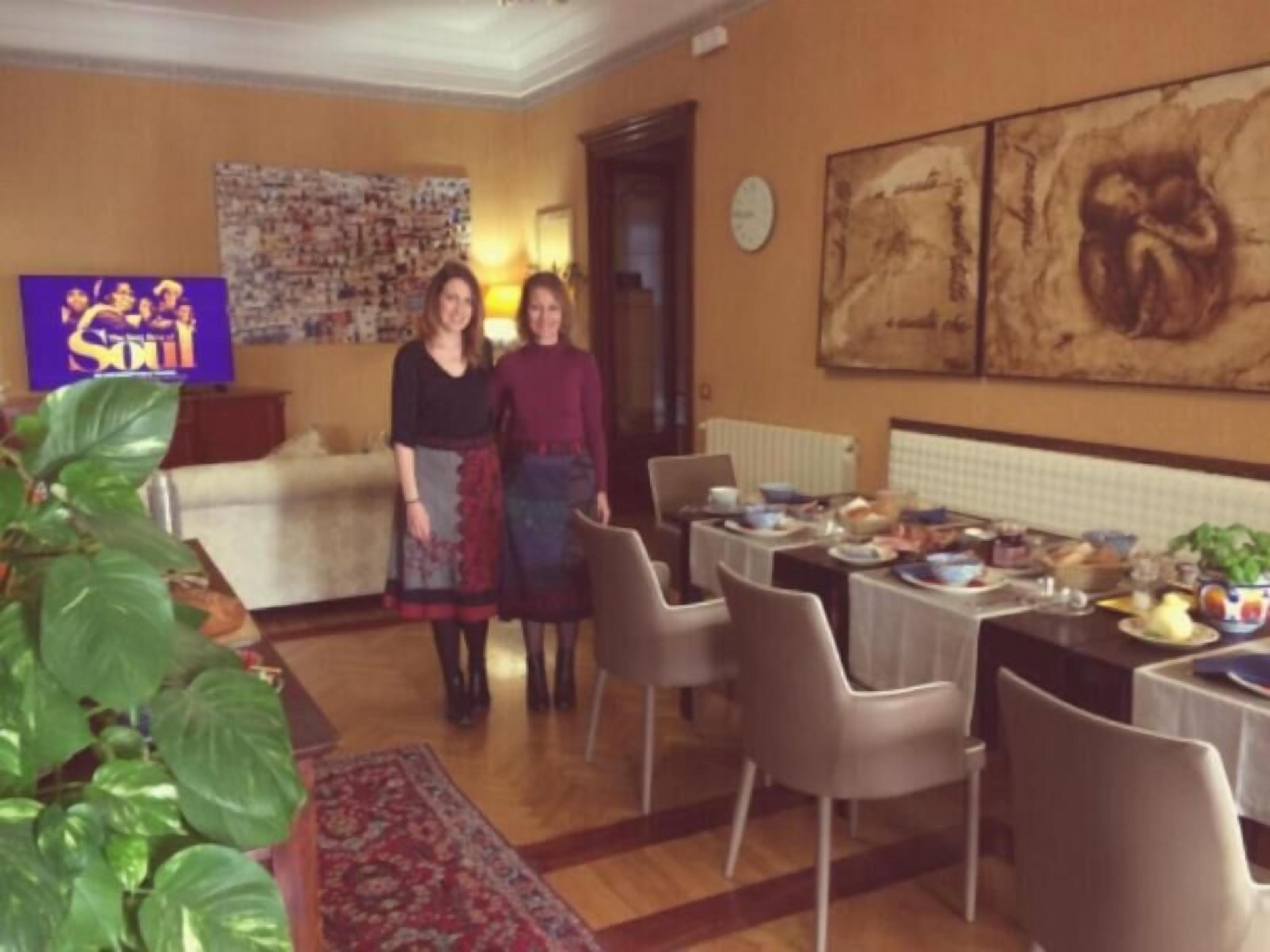 A dining area with a table set for a meal, a sofa, and a wall with a large painting.