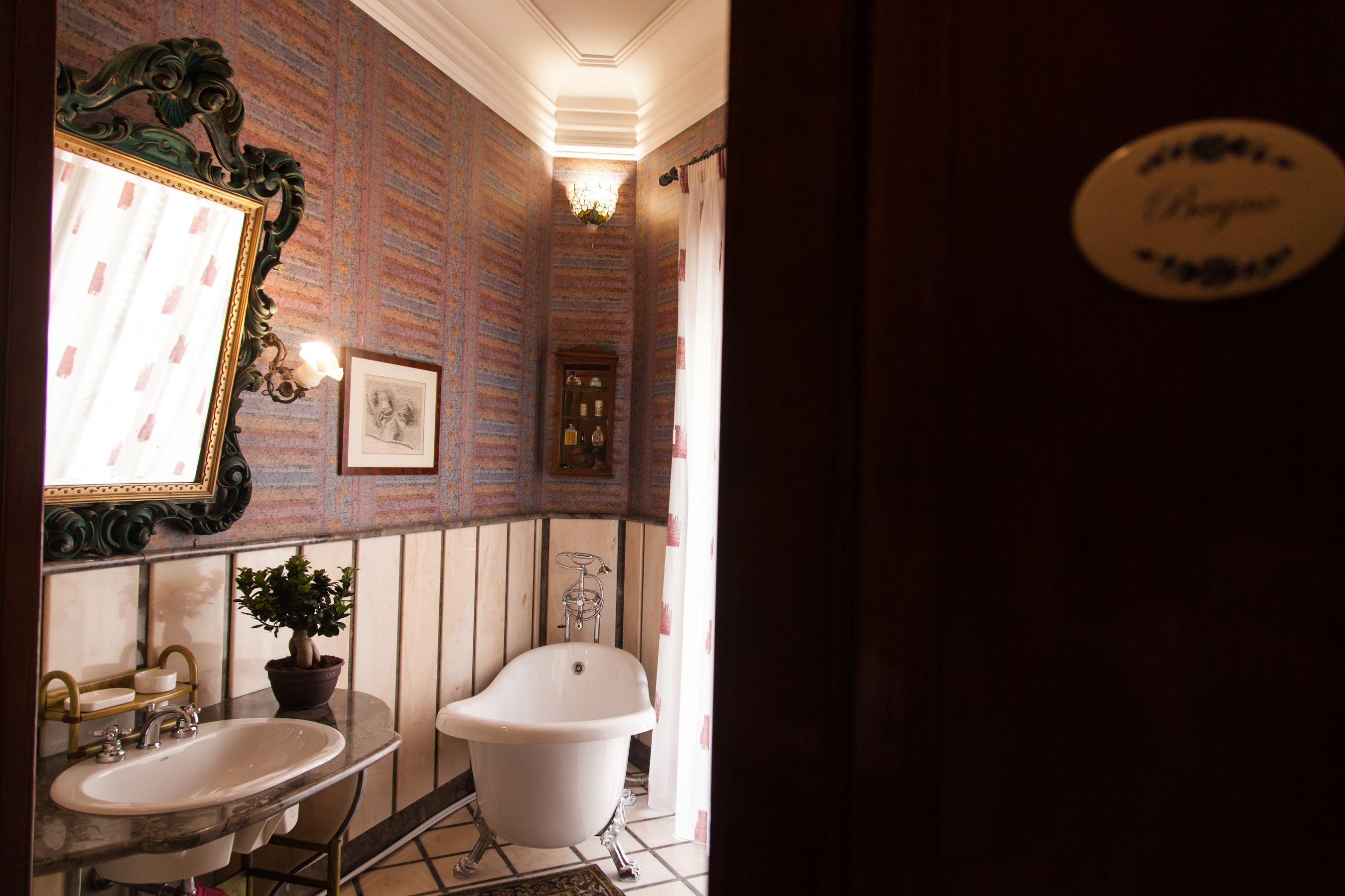 A bathroom with a bathtub, two sinks, a mirror, and a potted plant.