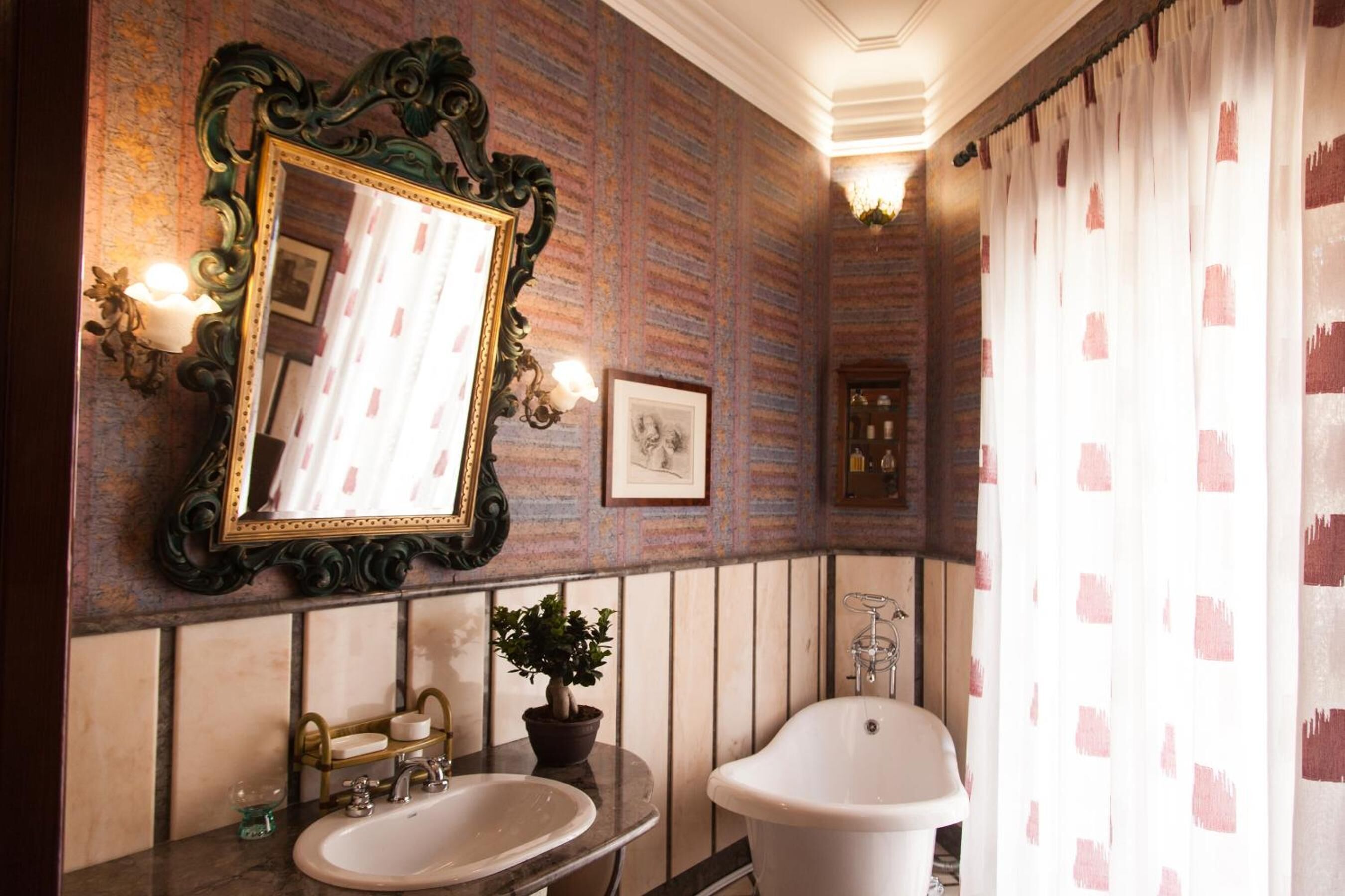 Une salle de bain avec un grand miroir, un lavabo, une baignoire et une plante en pot.