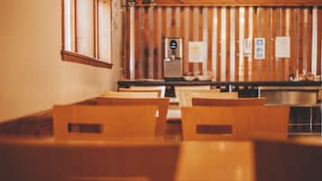 A row of wooden chairs and tables in a room with wooden paneling on the walls.