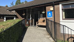 A hostel with a covered entrance, a sign indicating it's in Scotland, and a pathway leading to the entrance. - Crianlarich Youth Hostel (Crianlarich)