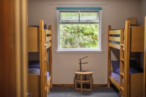 Una habitación con literas, una mesita pequeña y una ventana con vistas a zonas verdes.