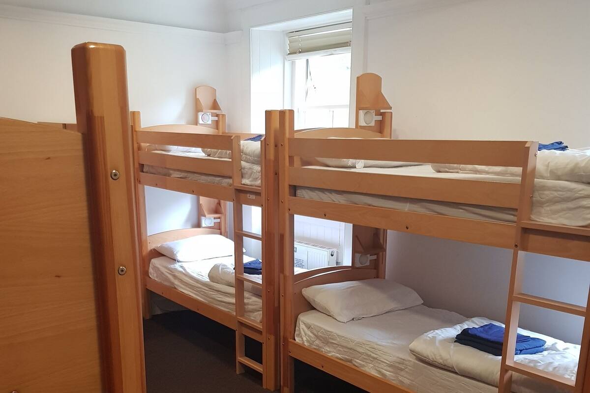 Ein Schlafzimmer mit Etagenbetten, Holzrahmen und weißer Bettwäsche.
