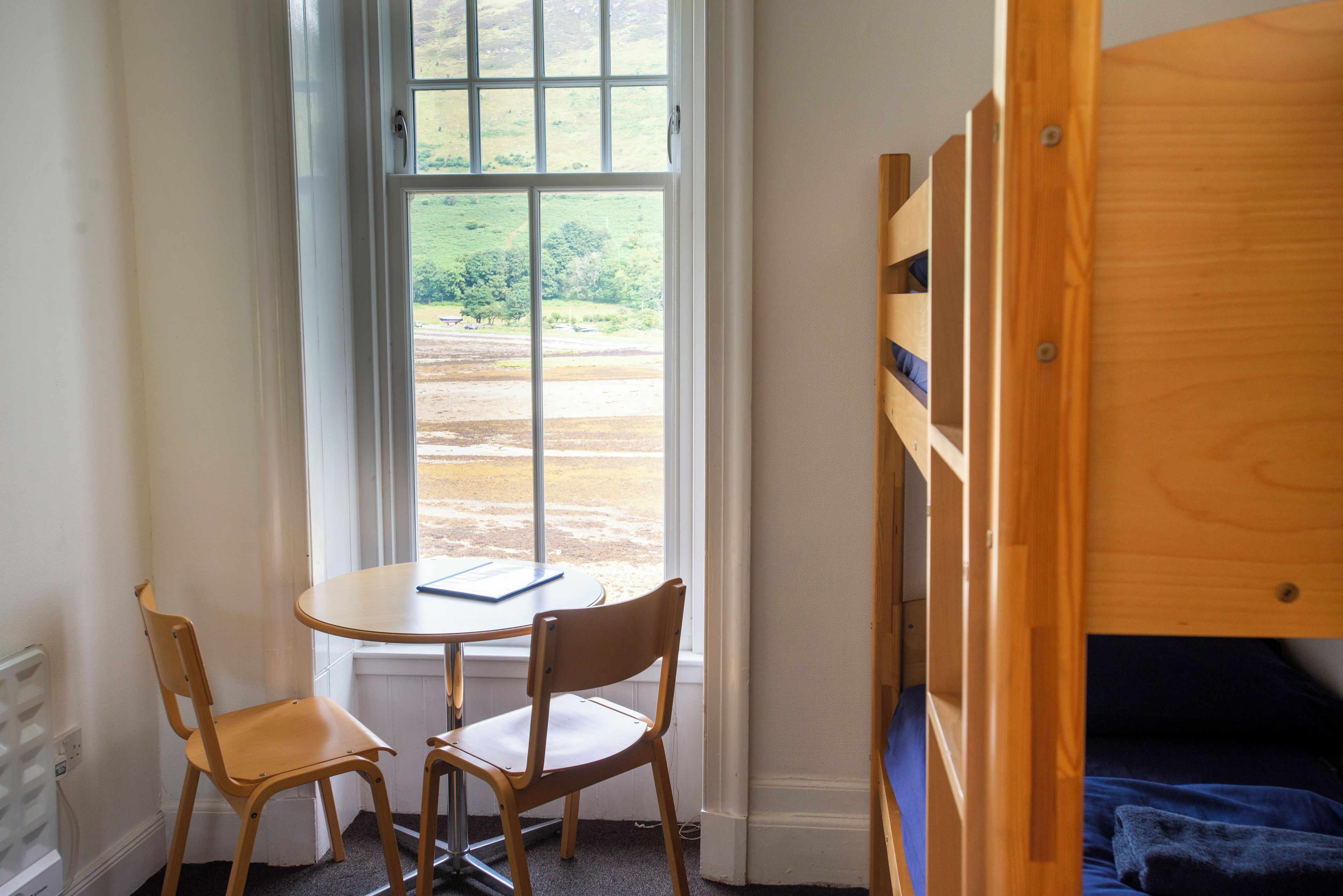 Una habitación con literas, una mesita pequeña y dos sillas.
