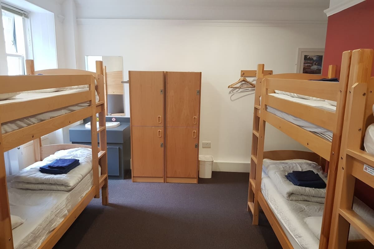 Ein Schlafraum mit Etagenbetten, einem Schreibtisch, einem Kleiderschrank und einem Badezimmer.