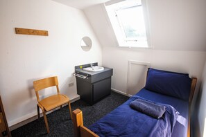 A small, single-room accommodation with a bed, a chair, a sink, and a window. - Lochranza Youth Hostel (Isle of Arran)