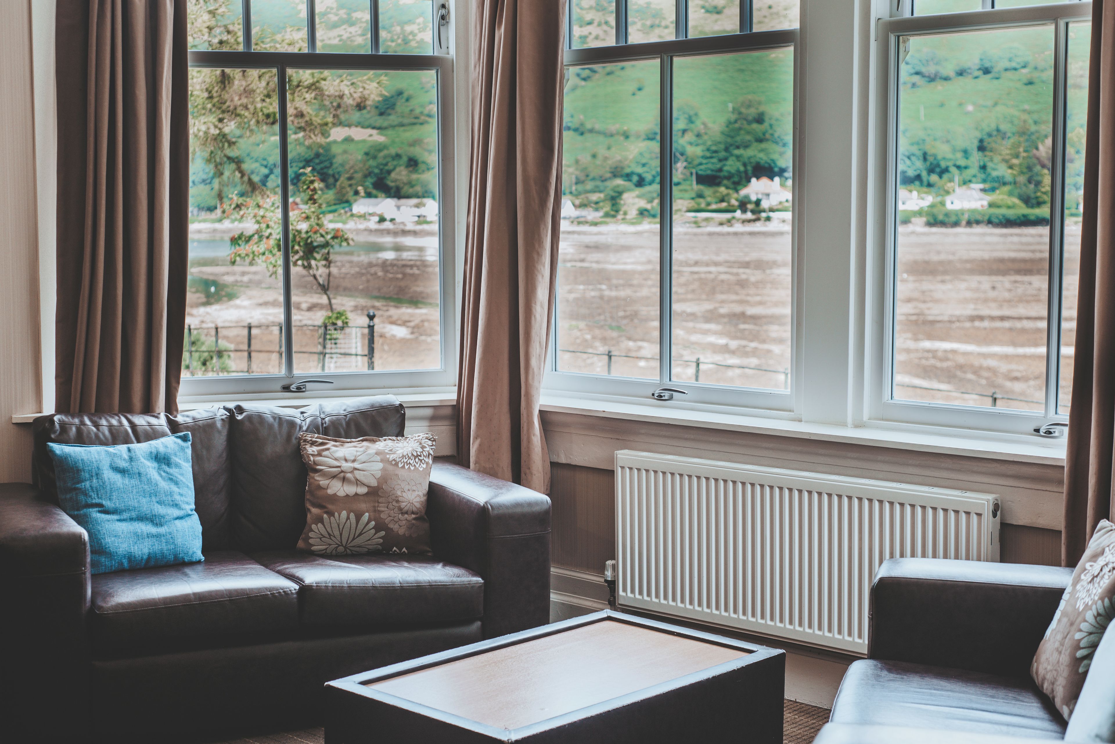 Una habitación con sofá de cuero, una mesa de centro y vistas a un paisaje verde a través de amplias ventanas.