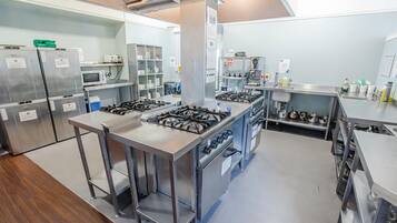A commercial kitchen with stainless steel appliances, including a range, ovens, and a microwave.