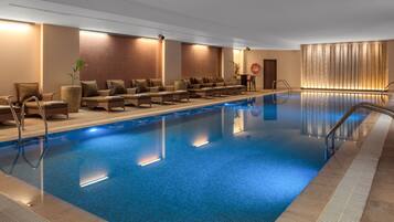 A hotel swimming pool with lounge chairs and a sunbed area.